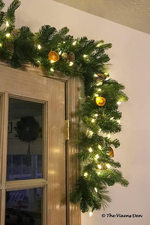 a lit garland embellished with pinecones and DIY dried orange slice ornaments