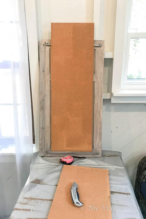 cork board cut in half length-wise and leaned against craft cabinet door for measuring