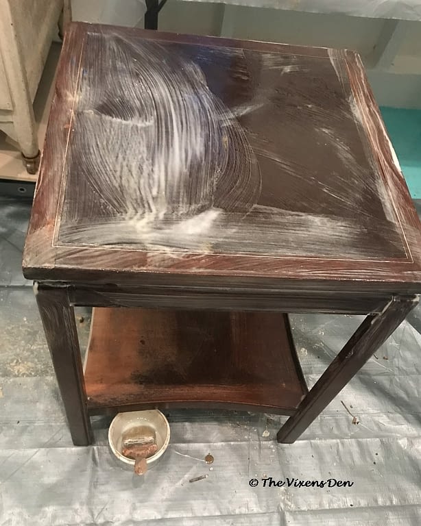 cherry side table with a coat of furniture finish remover painted onto the surface