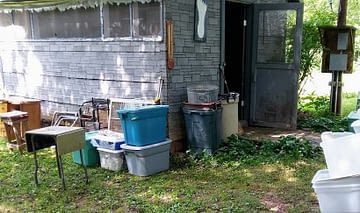 old shed with asphalt siding and totes